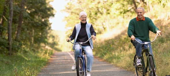 Senior couple cycling along bike path in woods