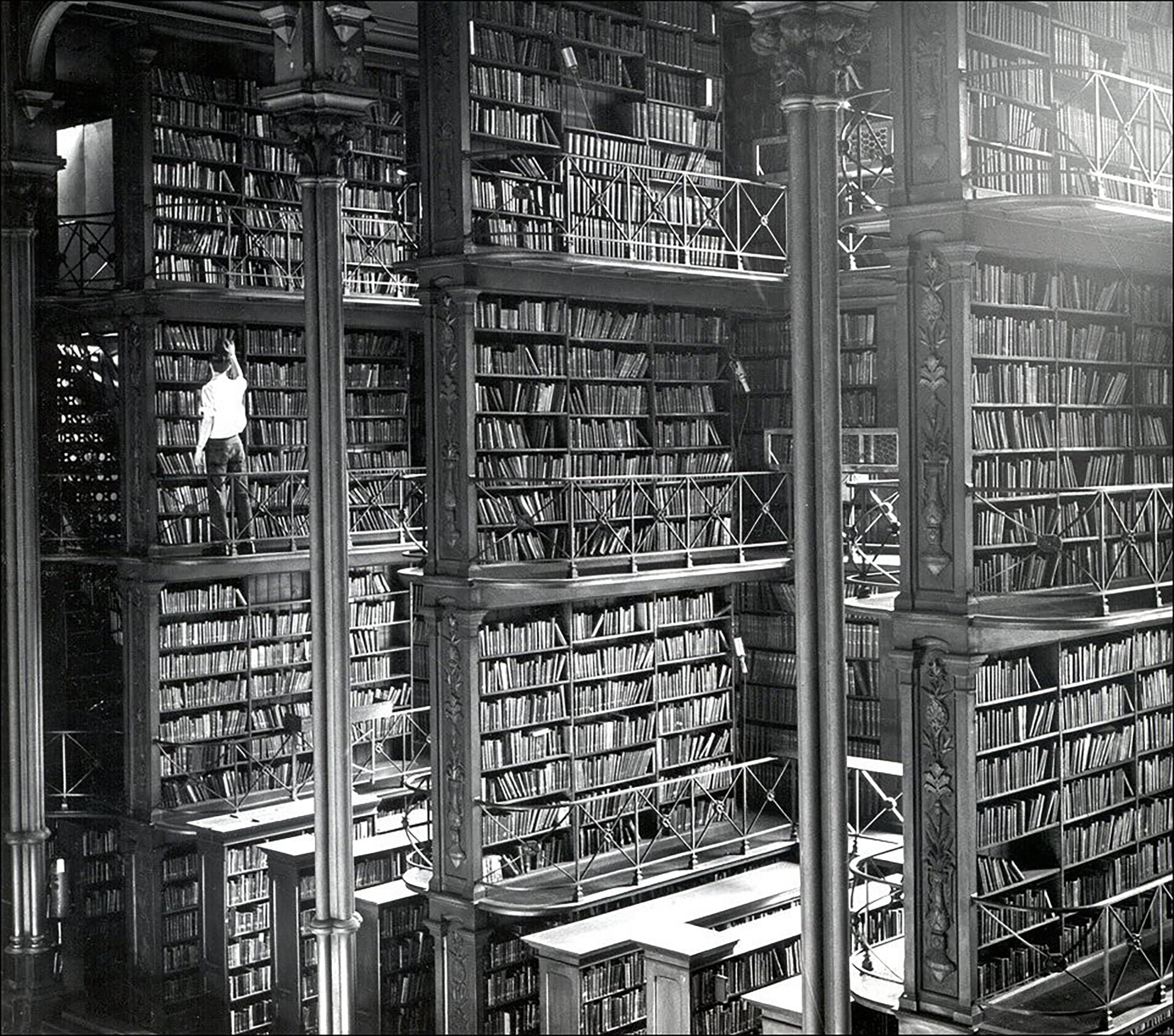 Black and white photo of the Cincinnati Old Main Library taken 1874. There is a single person for scale and the library is massive in size with several levels seen in the single photo alone. Unfortunately the library was torn down in 1955.
