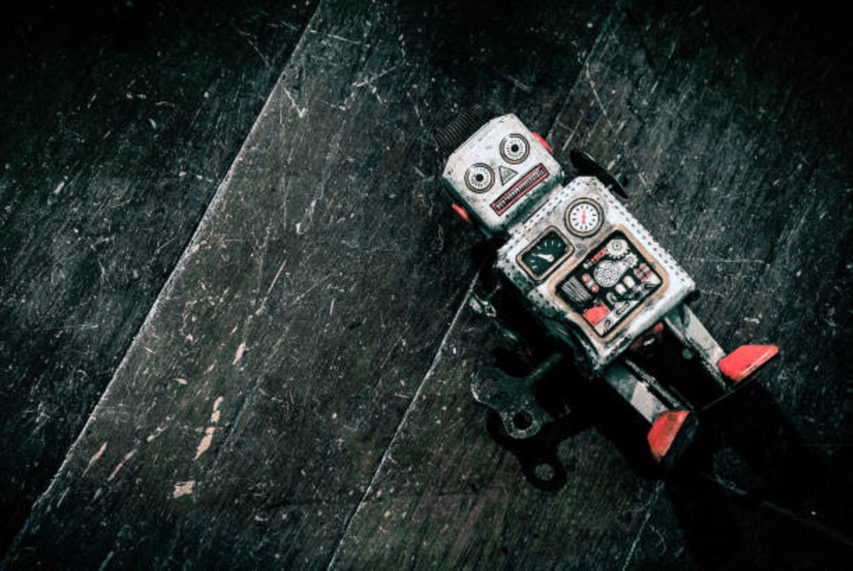 sad beat up old retro robot on a wooden floor shot from above