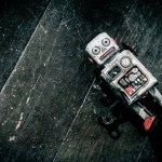 sad beat up old retro robot on a wooden floor shot from above